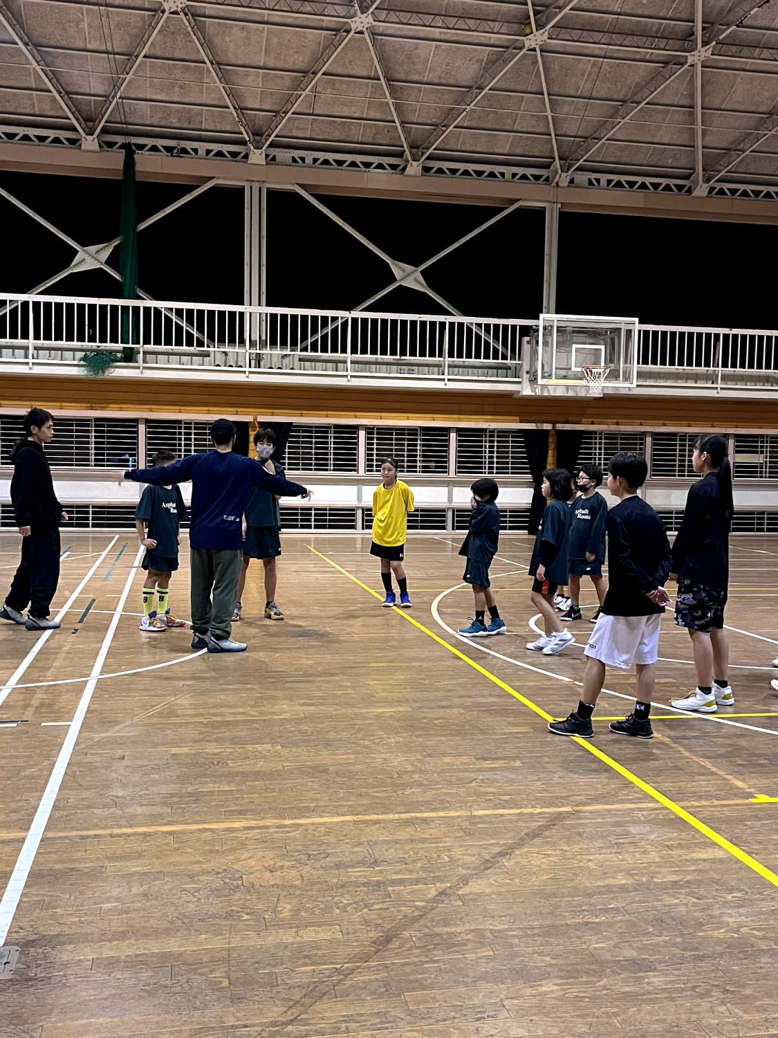 複数のスクール生がコーチの周りに集まっている様子の写真