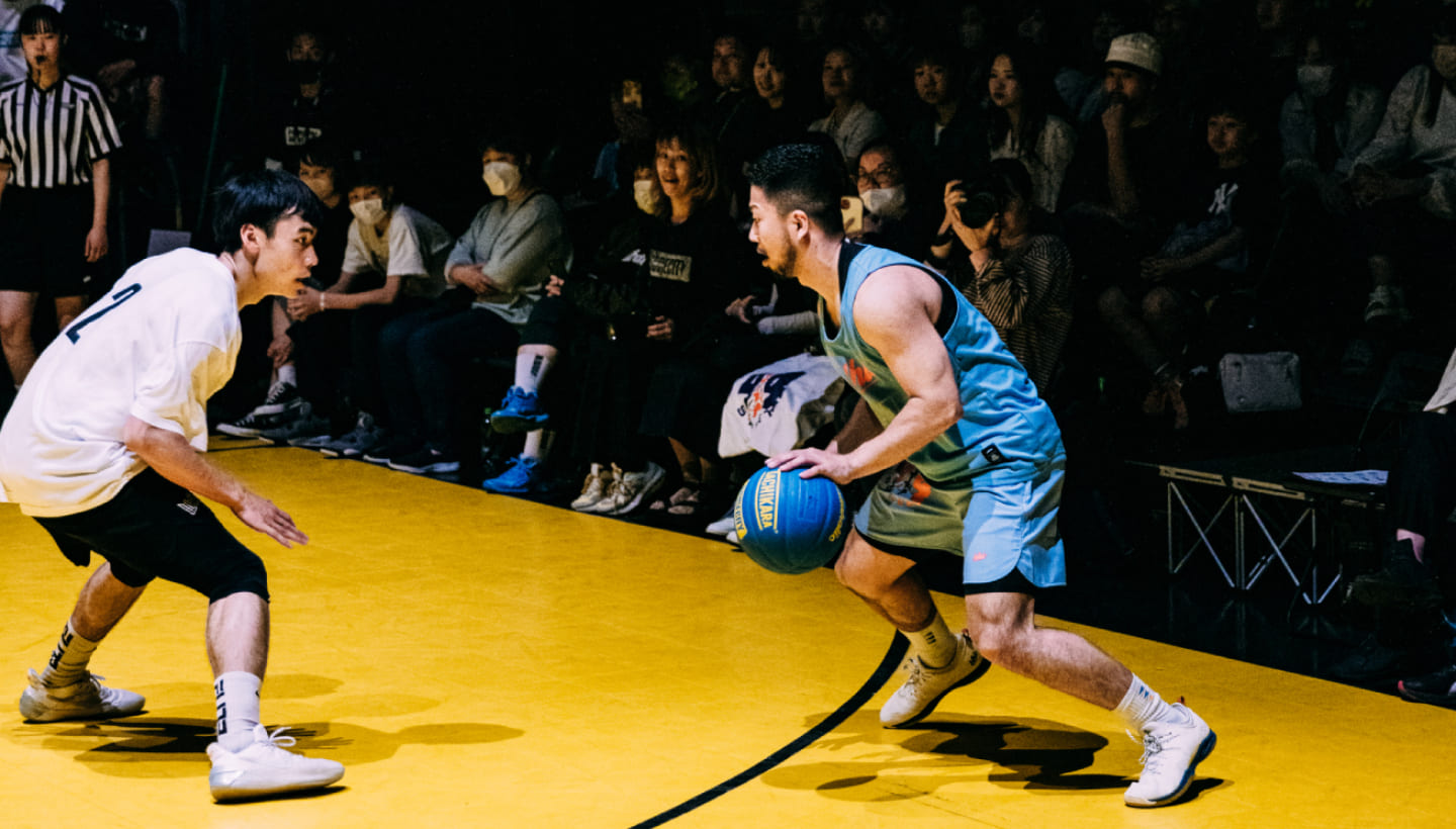 大勢の観衆に見守られながら、複数人がバスケットボールをしている様子の写真