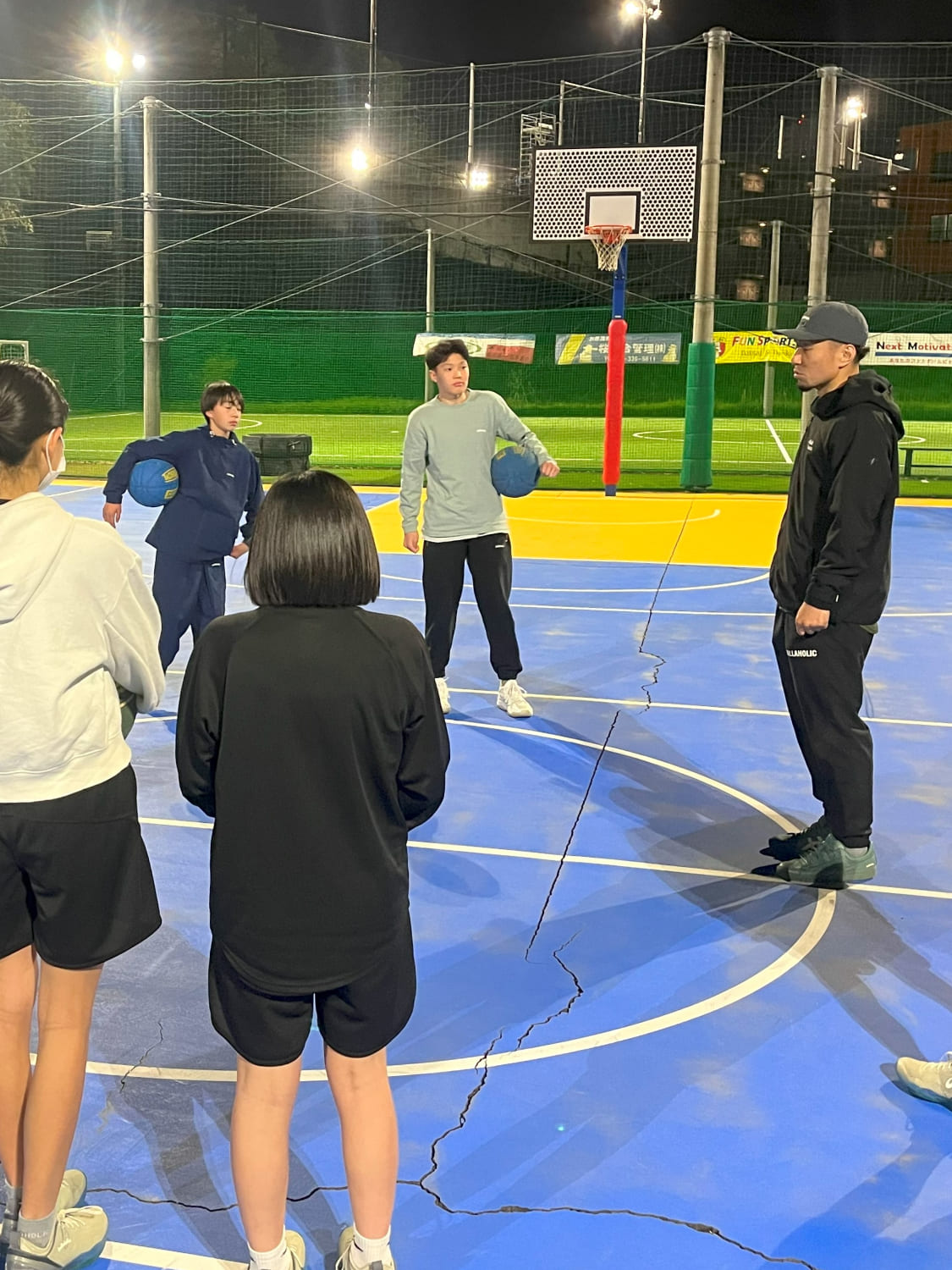 複数人のスクール生がコーチの話を聞いている様子の写真