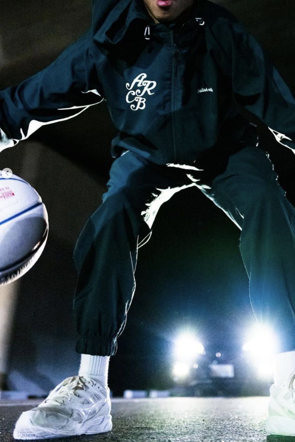 緑のパーカーを着た人が野外でドリブルをしている様子の写真