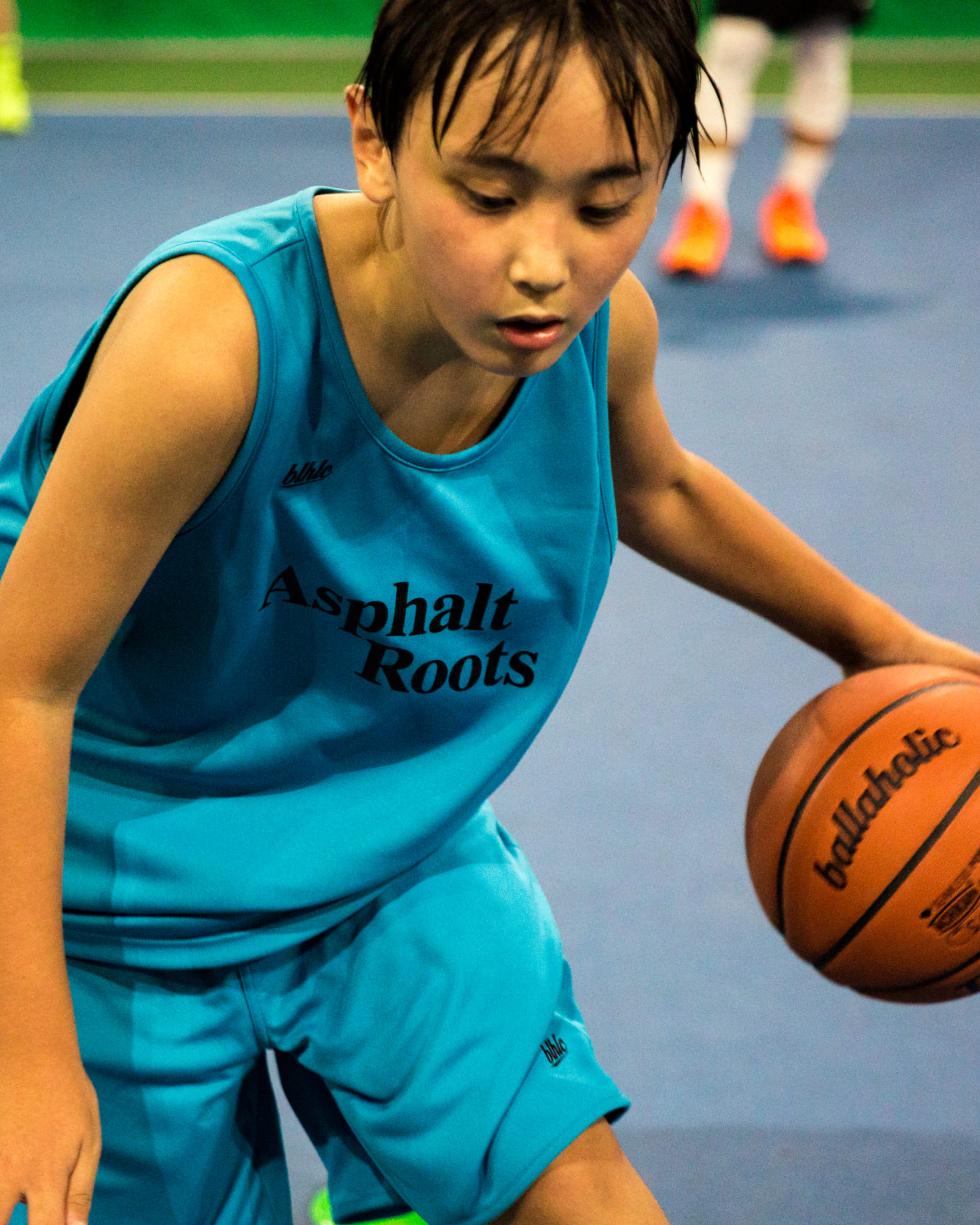 青い服をきた女の子がドリブルをしている様子の写真