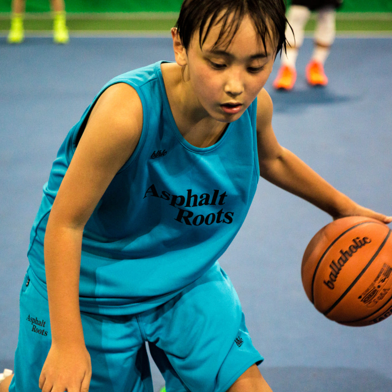 青い服を着た女の子がバスケットボールをしている様子の写真