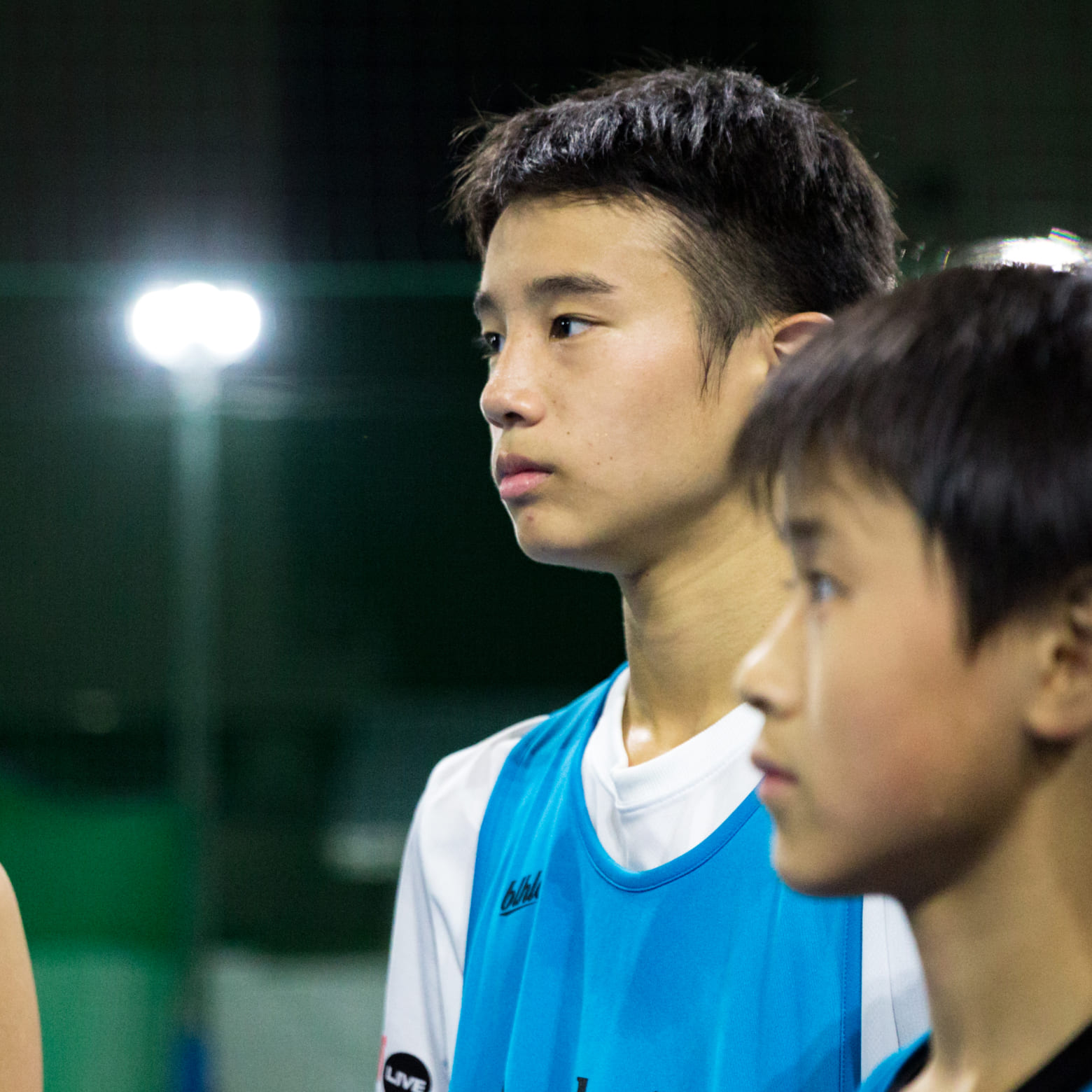 青い服をきた青年が真剣な眼差しをしている様子の写真